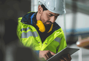 Engineer using a tablet on-site to review project data as part of a digital twin construction workflow for connected asset management.